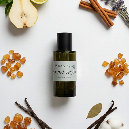 A bottle of 'Spiced Legend' cologne surrounded by vanilla beans, cinnamon sticks, a lemon, a pear, and lavender on a white background.